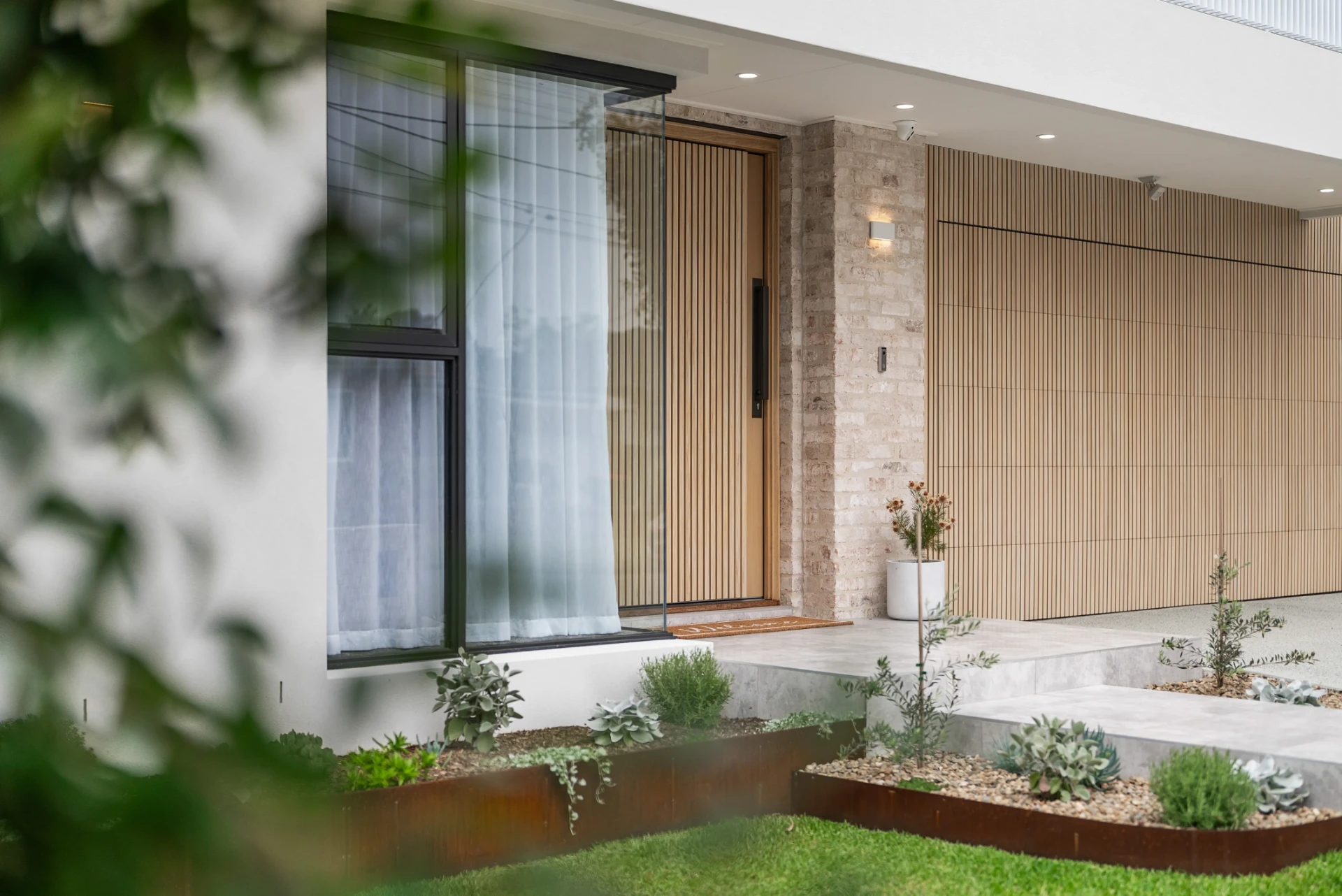 Modern Bayview home entry with timber door, stone cladding and landscaped garden