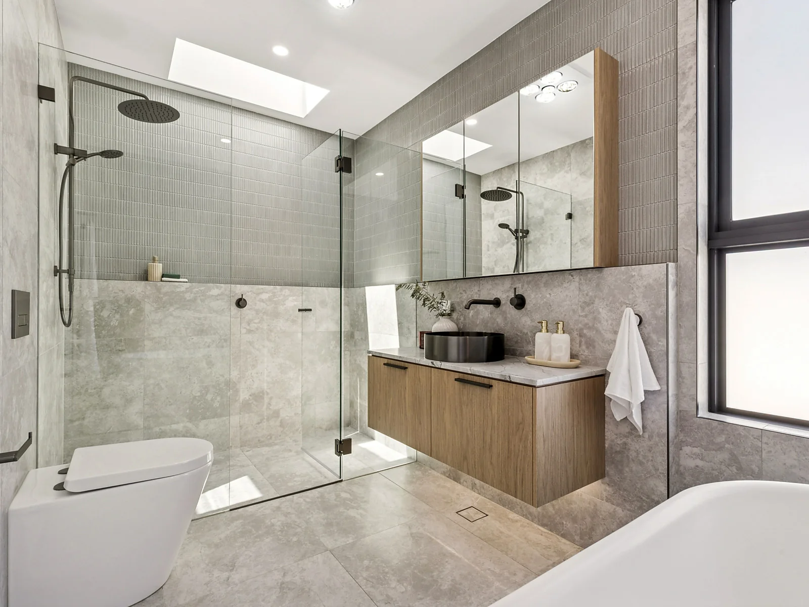 Luxury bathroom with natural stone tiles, oak vanity and frameless shower by Bayview Homes